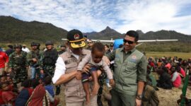 Dalam kunjungan ke Papua, Menko Muhadjir menggendong salah satu anak Papua. 