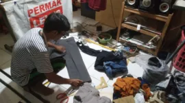 Pak Levi's saat memotong celana pelanggan.