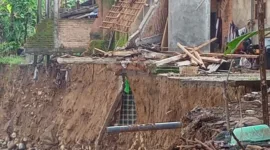 Sebuah rumah sebagian hanyut terbawa arus.