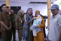 Plt.Ketua TP.PKK Kabupaten Sidoarjo dr. Sriatun Subandi secara simbolis berikan bantuan pangan kepada warga.