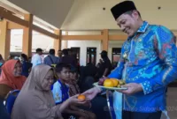 Plt Bupati Sidoarjo Subandi berikan buah kepada warga yang sedang mengambil bantuan beras CPP di Kedungsukodani, Kecamatan Balongbendo. 