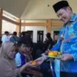 Plt Bupati Sidoarjo Subandi berikan buah kepada warga yang sedang mengambil bantuan beras CPP di Kedungsukodani, Kecamatan Balongbendo. 