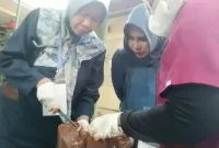 Mimik Idayana bersama warga setempat saat melihat pemotongan daging kurban.