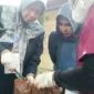 Mimik Idayana bersama warga setempat saat melihat pemotongan daging kurban.